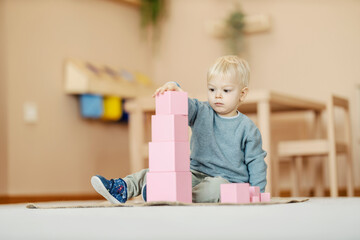 A child is playing with educational toys at nursery, he is building blocks tower.