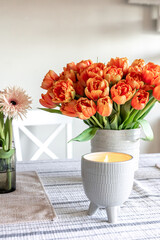 A bouquet of tulips and a candle on the table, close up.