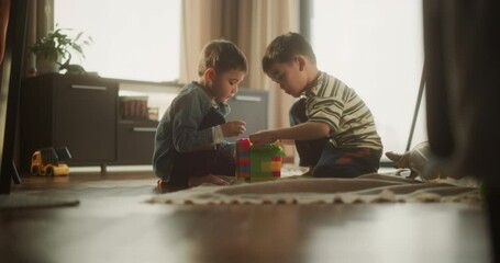Portrait of Two Male Asian Kids Playing with Colorful Building Blocks in Their Room During the Day. Big Brother Helping Younger Sibling to Construct a Toy House. Concept of Childhood and Innocence