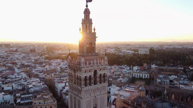 Aerial dolly out revealing Giralda tower in the famous European cathedral of Seville with scenic sunlight behind