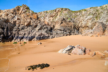 Kleine Felsen-Bucht mit Strand und Muschel bewachsenen Felsen