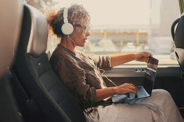 Mid age woman using computer inside transport bus vehicle during business or vacation travel....