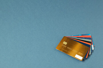 Gold color credit card, gift cards, discount cards, fan sales cards lie on a blue background. Pile...