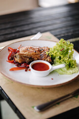 Crispy fried pork on the bone on a pillow of fried sweet onions and sweet bell peppers. sauce and fresh salad
