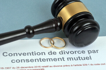 Concept de divorce par consentement mutuel avec des alliances et un marteau de juge sur fond bleu - obrazy, fototapety, plakaty