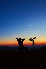 Man with astronomy telescope looking at the night sky, stars, planets, Moon and shooting stars.