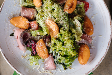 Warm salad with veal and apricots. Delicious food in restaurant. Wooden table