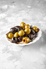 Delicious black and green olives in plate on gray background