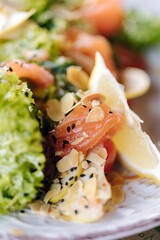 Fresh salad with salted red fish and nuts on wooden table
