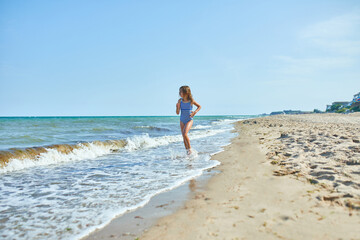 Happy, joyful little girl run on the beach