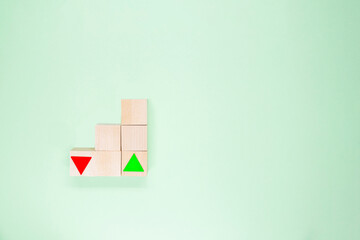 Pyramid of wooden cubes with green arrow up and red arrow down on the green background.