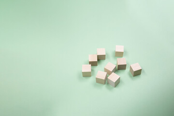 Wooden cubes randomly scattered on a green background. Copy space .