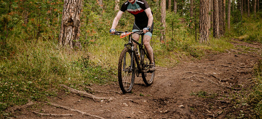 dirty man cyclist in mountain bike down forest trail