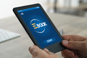 Man using e-book reader at wooden table indoors, closeup