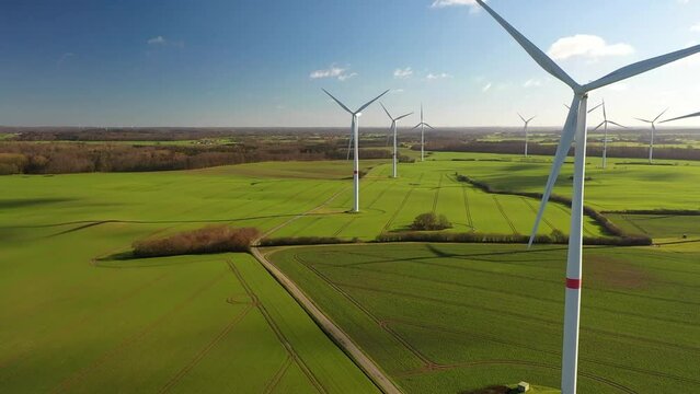 Aerial flying over renewable energy wind farm. Landscape with wind turbines in countryside. Agricultural fields on eco farm modern electric station renewable energy. 