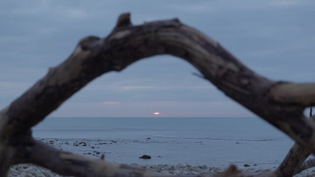 captured through weathered, rustic wooden frame rising sun casts a stunning glow over the calm sea during morning hours