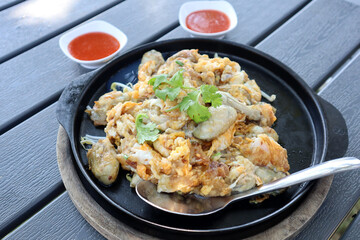 Popular Thai street food,  Fried 
 Oyster Omelette served on iron pan with spicy sauce. Chinese Food in Thailand.  