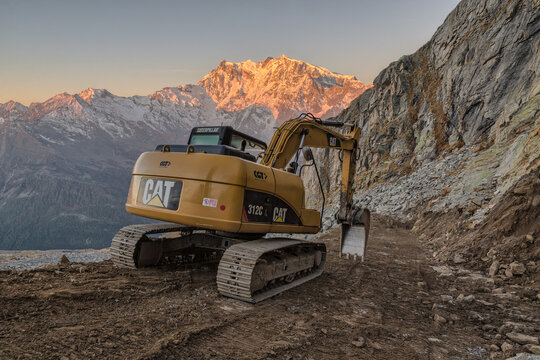 Work at high altitudes in the mountains. Caterpillar excavator building a dirt road. Caterpillar is the world's largest manufacturer of construction equipment. Construction of a mountain bike trail