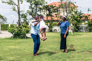 Fototapeta premium Portrait of enjoy happy love black family african american father and mother with little african girl child smiling and play having fun moments good time in park at home