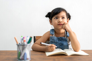 Naklejka premium Portrait enjoy happy little asian girl learn and study on table.Asian young girl writing and paint with paper book make homework in homeschool at home.Education