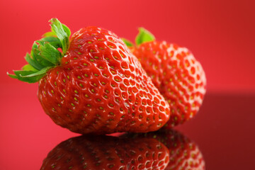 Strawberries on a red background. Two Fresh ripe strawberries on red, macro shot of fresh juicy berries, close up