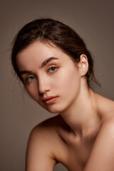 Fototapeta premium Natural makeup and healthy skin, wellness. Portrait of young beautiful girl with brown hair posing over dark grey studio background. Concept of beauty, skincare, cosmetology, plastic surgery, health