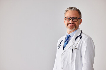 Portrait of a senior doctor with a stethoscope, standing at his workplace.