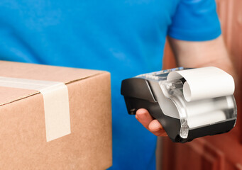 courier holds a terminal for payment and a parcel in his hands