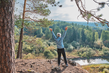 Senior female hiker on rock in nature park Deer streams, Russia