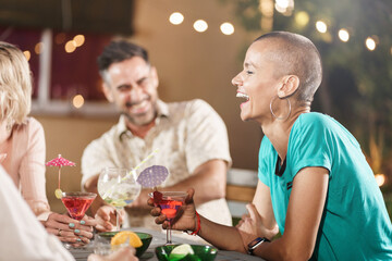Adult friends drinking cocktails and having great party time together - Cheerful woman with shaved hair laughing