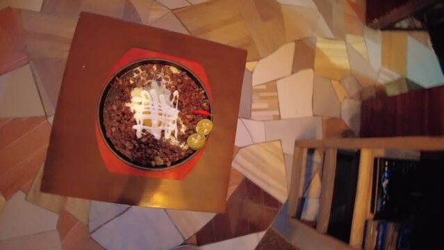 A top-view rotating shot of a sizzling pork sisig dish made in Bacolod City, Philippines.