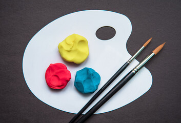 Colourful plasticine on the pallet on a dark background