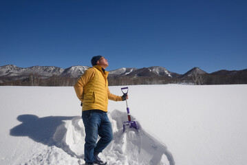 雪国で除雪をして疲労している日本人シニア男性