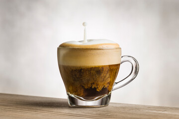 Cup of cappuccino with splashing milk on wooden table.