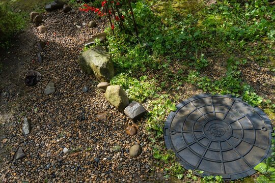 Drainage sewer system. Discharge of treated water from septic tank in summer cottage or personal plot. Luke black. Filtration field is covered with rubble and decorated with stones and plants.