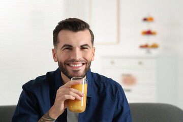 Handsome man with delicious smoothie at home. Space for text