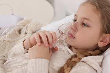 Obraz na płótnie Canvas Little girl using nebulizer for inhalation indoors, closeup