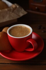 Delicious heart shaped cookies and cup of coffee on wooden table, closeup