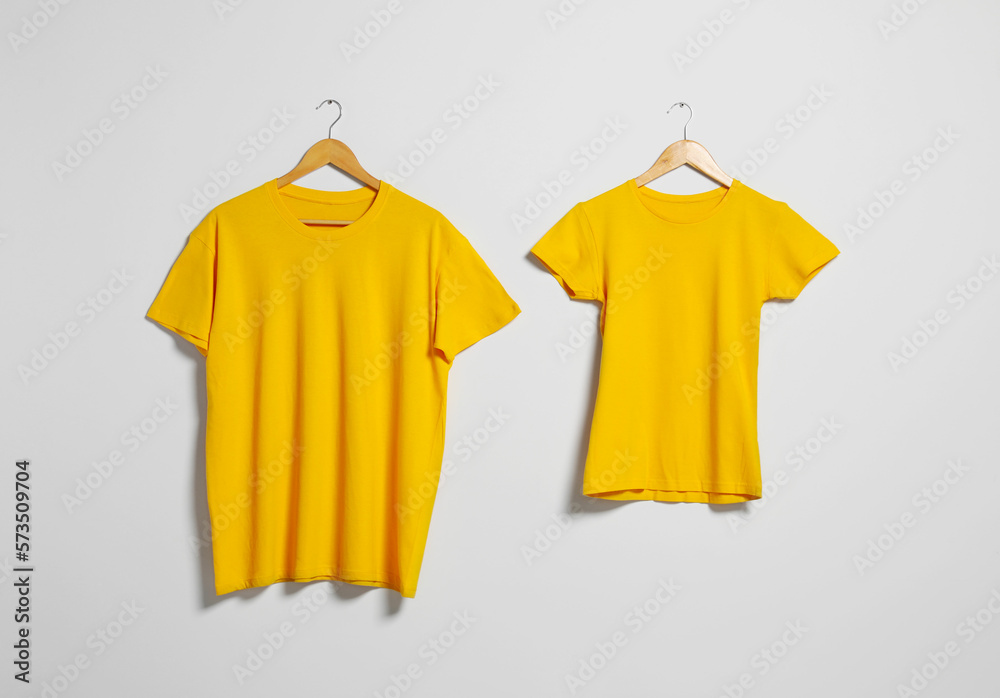 Wall mural Hangers with different t-shirts on light wall. Mockup for design - Wall murals