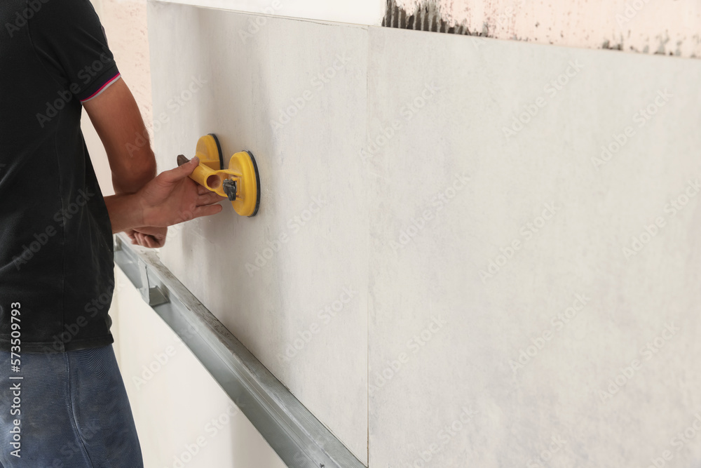 Sticker Worker installing wall tiles with vacuum holder indoors, closeup