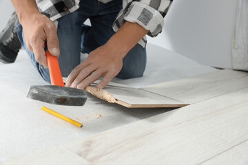 Fototapeta na wymiar Professional worker using hammer during installation of new laminate flooring, closeup