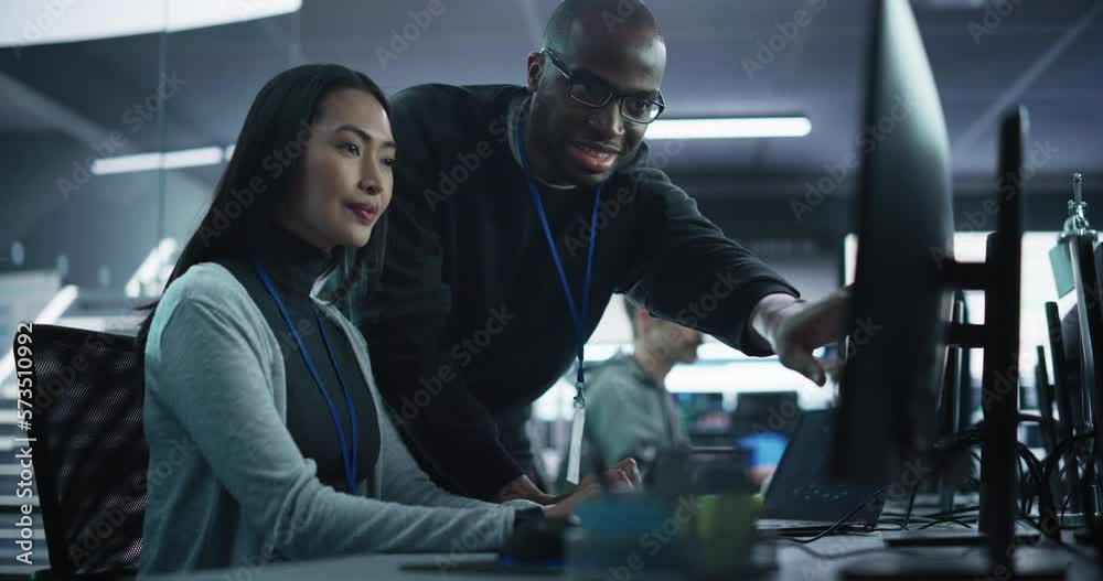 Aufkleber Two Diverse Multiethnic Colleagues Having a Conversation While Busy Working on a Team Project. Asian Female Designer Talking with an African Project Manager. Teamwork in Technology Laboratory