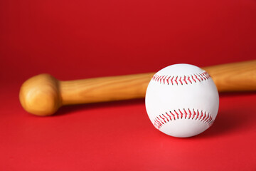 Wooden baseball bat and ball on red background. Sports equipment