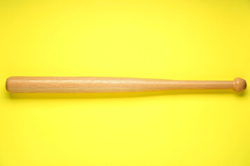 Wooden baseball bat on yellow background, top view. Sports equipment