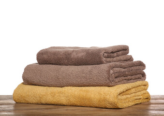 Soft colorful terry towels on wooden table against white background