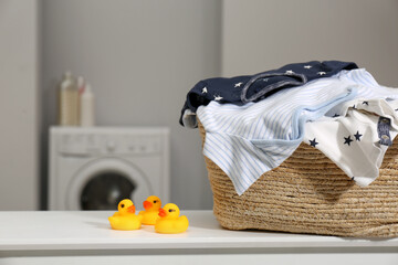 Fototapeta na wymiar Laundry basket with baby clothes and rubber ducks on table in bathroom, closeup. Space for text