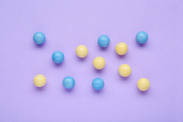 Many bright chewy gumballs on lilac background, flat lay