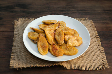 Tasty deep fried banana slices on wooden table