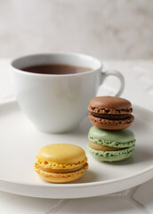Colorful french macarons or macaroons (almond cookies) with a cup of tea on the  white background. Copy space for text