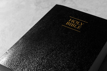 Bible with black cover on light gray table, closeup. Christian religious book